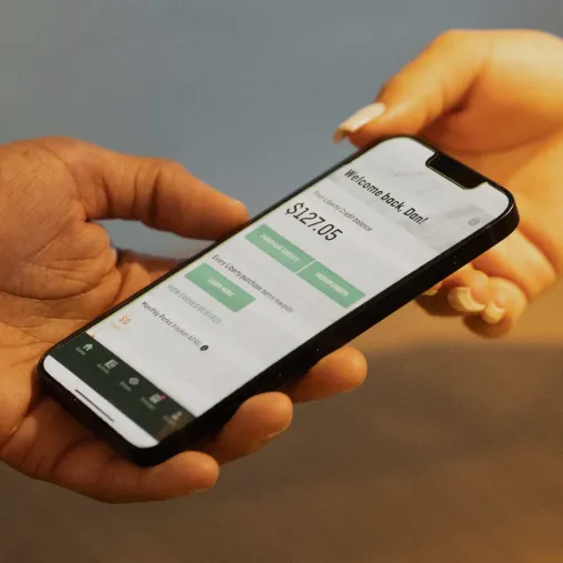 Two hands holding a phone featuring the Liberty Wallet app